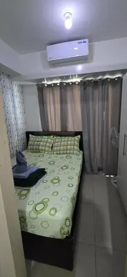 a bedroom with a bed with a green comforter at Jhang places sea residence in Manila