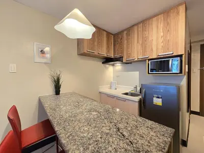 a small kitchen with a counter and a refrigerator at 1BR Condotel Ridgewood Towers Taguig City #RW16 in Manila