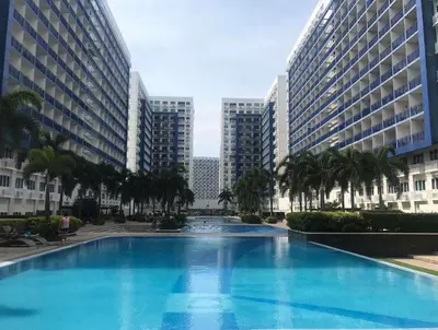 a large swimming pool with palm trees and buildings at Sea Residence in Manila