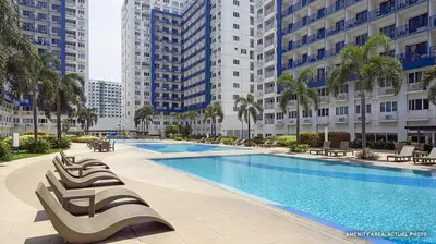 a large swimming pool with lounge chairs and buildings at Sea Residence in Manila