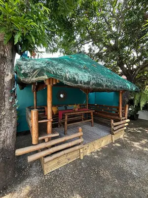 a hut with a green umbrella and benches under a tree at The Barkly House Staycation in Biñan
