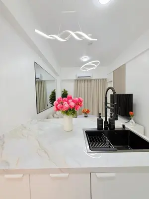 a kitchen with a sink and pink flowers on a counter at Le Luxe 102 by Ara li in Manila