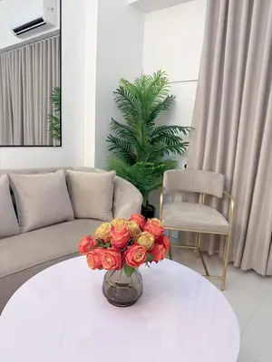 a vase of flowers on a white table in a living room at Le Luxe 102 by Ara li in Manila
