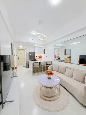 a white living room with a couch and a table at Le Luxe 102 by Ara li in Manila