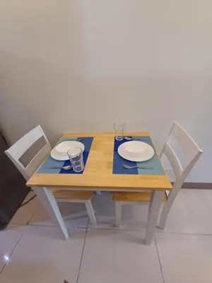 a wooden table with two chairs and two plates and glasses at Cozy and Comfortable 1BedRoom at Coast Residences in Manila