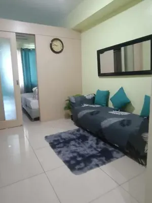 a bedroom with a bed and a clock on the wall at Ederly Place at Sea Residences near Moa in Manila