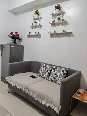 a couch in a room with shelves on the wall at Kim Place at Sea Residences near Moa in Manila