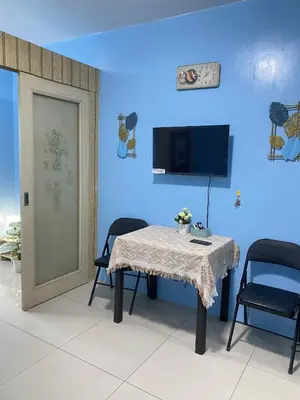 a blue room with a table and chairs and a tv at Kim Place at Sea Residences near Moa in Manila
