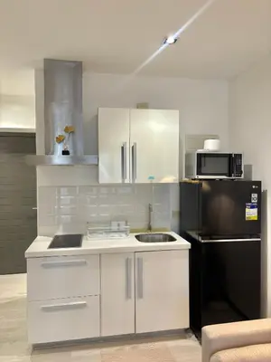 a kitchen with white cabinets and a black refrigerator at ElixirStaycation at Knightsbridge Residences in Manila