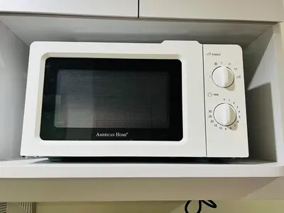 a white microwave sitting on a shelf in a kitchen at 1BR luxury bed, movie room, swimming pool access in Manila