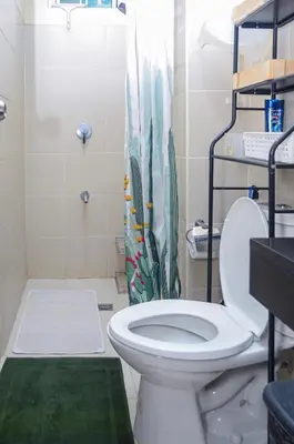 a bathroom with a white toilet and a shower at Urban Escape for You & Your Pet in Manila