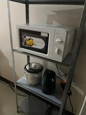 a microwave oven sitting on a shelf with a pot at studio flat at 101 Newport Boulevard in Manila