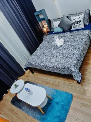 a living room with a bed and a blue rug at Tessa's Place Staycation in Biñan