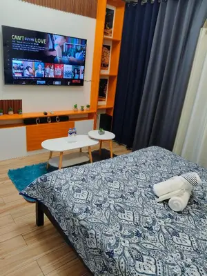 a bedroom with a bed and a tv and a table at Tessa's Place Staycation in Biñan