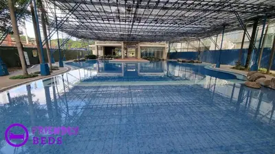 a large swimming pool with blue water in a building at 2BR with 2 balconies condo and Pool in Pasig in Manila