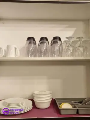 a shelf filled with wine glasses and bowls and plates at 2BR with 2 balconies condo and Pool in Pasig in Manila