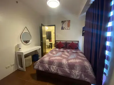 a bedroom with a bed and a sink and a mirror at 2BR with 2 balconies condo and Pool in Pasig in Manila