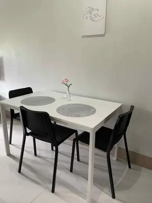 a white table with chairs and a vase of flowers on it at 10 minutes from MOA - Cozy Condo with Hot Shower & Balcony in Manila