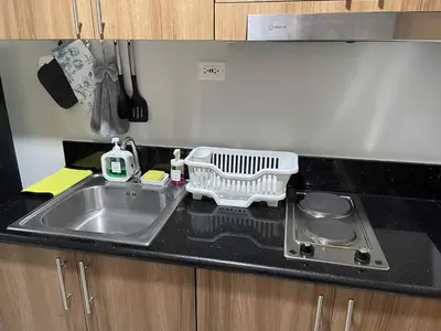 a kitchen sink with a dish drying rack next to it at 10 minutes from MOA - Cozy Condo with Hot Shower & Balcony in Manila