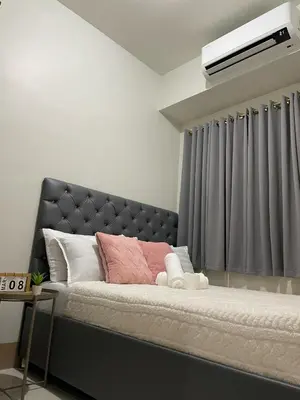 a bedroom with a large bed with a gray headboard at 10 minutes from MOA - Cozy Condo with Hot Shower & Balcony in Manila