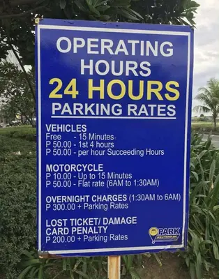a sign for a parking hours and parking rates at 10 minutes from MOA - Cozy Condo with Hot Shower & Balcony in Manila