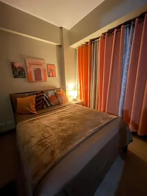 a bedroom with a large bed with orange curtains at NAIA T3 Two Palmtree Villas 3-5mins away from Resorts World Casino Manila in Manila
