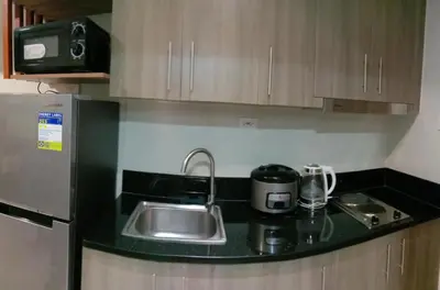 a kitchen counter with a sink and a microwave at fame residence staycation in Manila