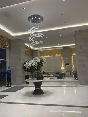 a man standing in a lobby with a table with flowers at fame residence staycation in Manila