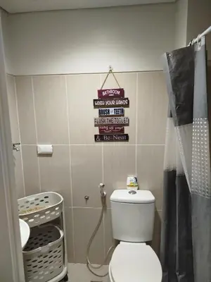 a bathroom with a toilet and a sign on the wall at Dash Shell Residences in Manila