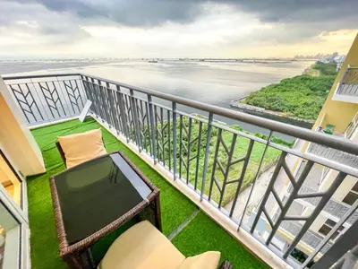 a balcony with a television and a view of the water at Bayshore 9g 4br in Manila