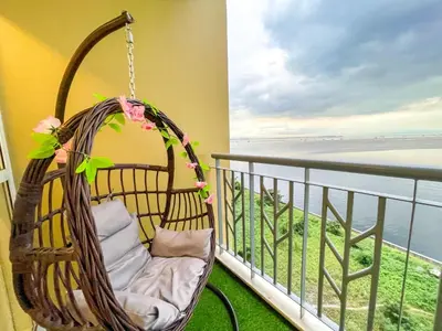 a hanging chair on a balcony overlooking the ocean at Bayshore 9g 4br in Manila