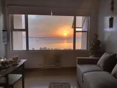 a living room with a large window with a sunset at Chic Haven in Manila