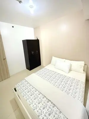 a bedroom with a large bed with a black cabinet at Shore Residences 2 Bedroom with Balcony Near NAIA Airport MOA in Manila