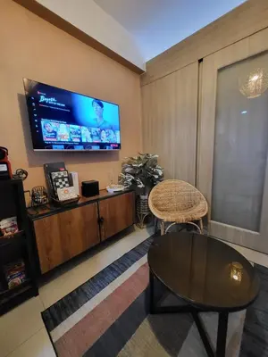 a living room with a table and a tv on the wall at Balay Maria in Manila