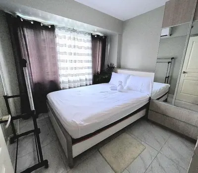 a bedroom with a bed and a window with a tripod at Condotel nearby MOA with Pool Access in Manila