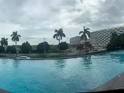 a swimming pool in front of a hotel with palm trees at Condotel nearby MOA with Pool Access in Manila