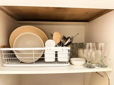 a shelf with plates and utensils on it at Mariels Staycation in Manila