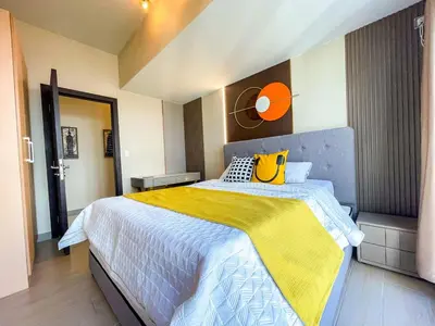 a bedroom with a large bed with a yellow blanket at Luxury 2BR Penthouse Across Uptown BGC I Modern in Manila
