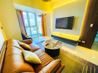 a living room with a brown leather couch and a table at Luxury 2BR Penthouse Across Uptown BGC I Modern in Manila