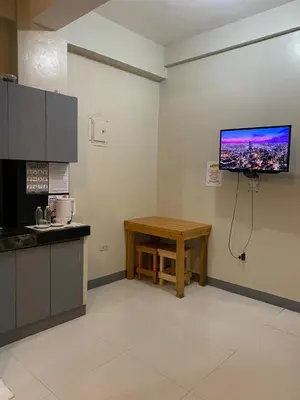 a kitchen with a table and a tv on the wall at P3k suites barkada family room in Manila