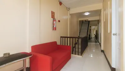 a living room with a red couch and a staircase at J and T Jamich Suites by RedDoorz in Manila
