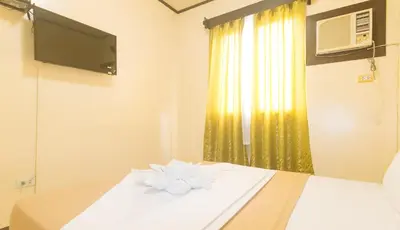 a room with a bed with a television and a window at J and T Jamich Suites by RedDoorz in Manila