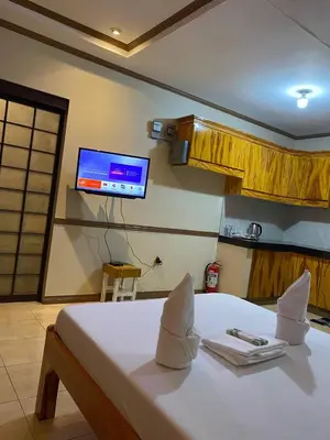 a bedroom with a white bed with a tv on the wall at P3k suites barkada family room in Manila