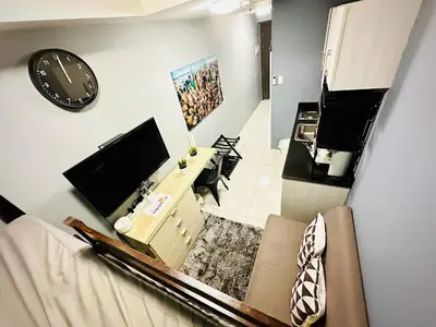 a living room with a television and a clock on the wall at STYLISH LUXE APARTMENT in SMDC GREEN RESIDENCES in Manila