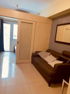 a living room with a couch and a sliding door at Jazz Residences Tower B Makati in Manila