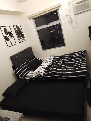 a black bed in a room with a window at MJ Luxe Stays in Manila