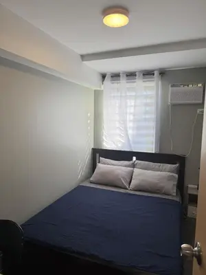 a bedroom with a blue bed with a window at 2BR Apartment in Pasig City in Manila