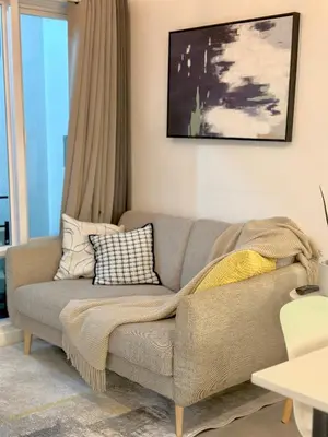 a living room with a gray couch with pillows at Sea Residences 2BR Pool View Unit for 4-8 pax - Beehive Stay MOA in Manila