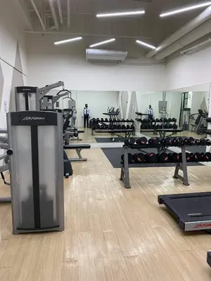 a gym with rows of fitness equipment and people in the background at Laidback Cavern at Studio City Alabang in Manila
