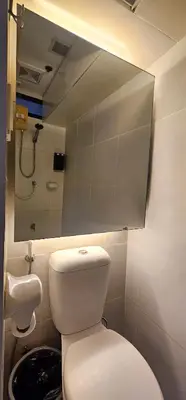 a bathroom with a toilet and a sink and a mirror at Laidback Cavern at Studio City Alabang in Manila